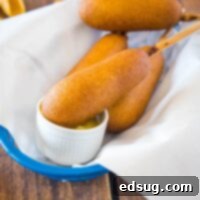 close up corn dog dipping in mustard