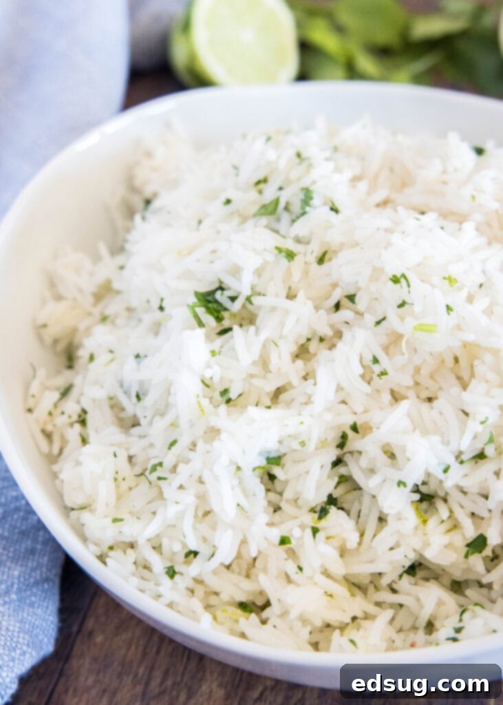 A serving of fluffy cilantro lime rice in a white bowl, garnished with fresh cilantro, on a rustic wooden table, ready to be enjoyed.
