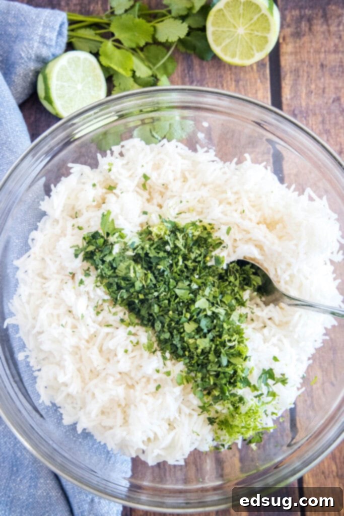 A cook's hands adding freshly chopped cilantro and a squeeze of lime juice to a bowl of warm, fluffy rice, preparing to mix.