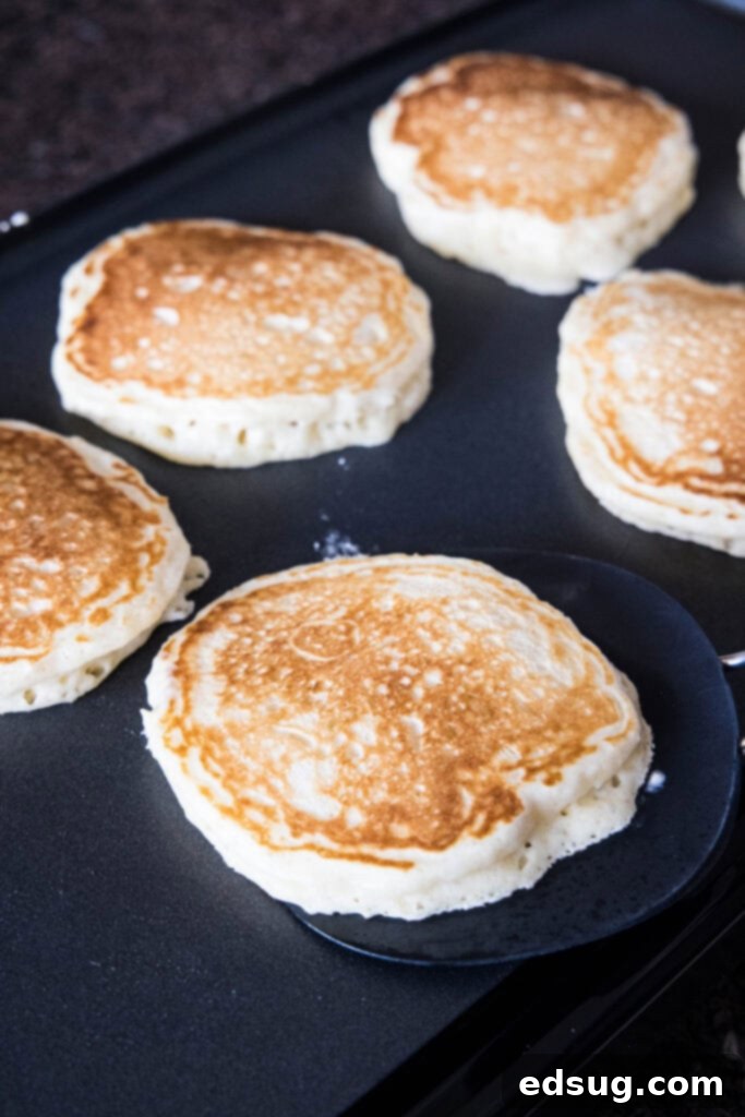 Several lemon pancakes sizzling and bubbling on a hot griddle