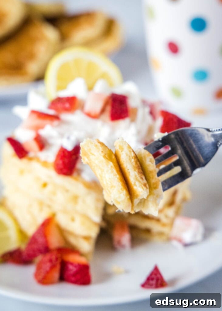 A fork spearing a piece of fluffy lemon pancake, ready to be eaten