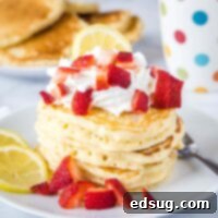 stack of lemon pancakes on white plate with strawberries