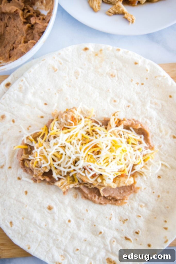 filling a tortilla with beans, chicken and cheese