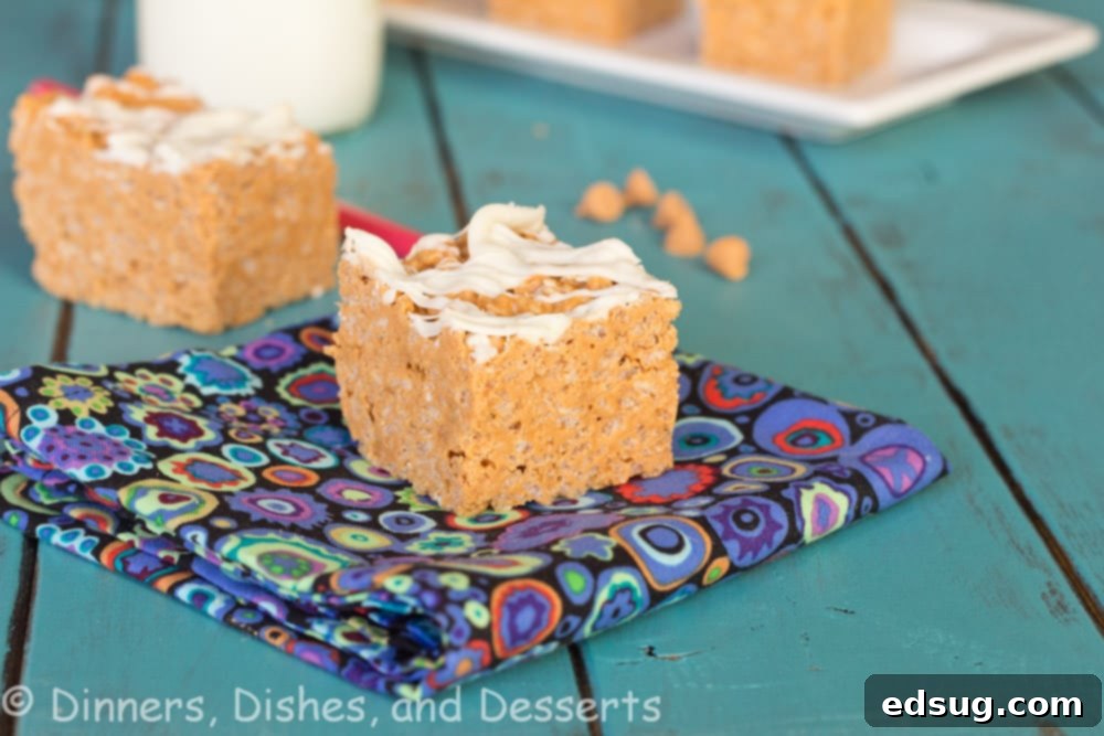 A freshly made batch of Peanut Butter Butterscotch Krispie Treats in a pan, with white chocolate drizzle.