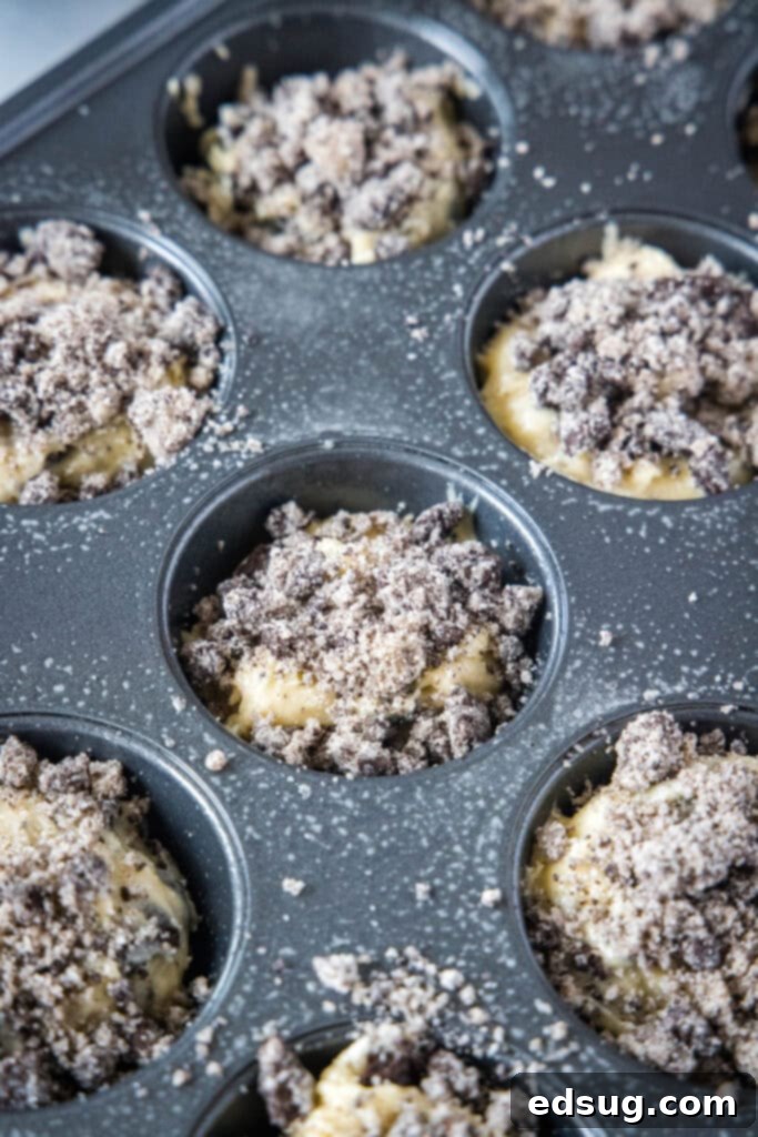 Oreo muffin batter in muffin tins with streusel topping before baking