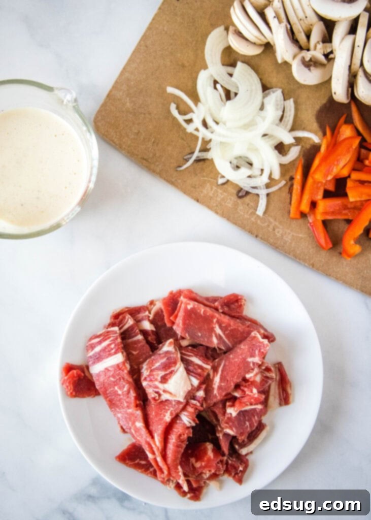 Philly Steakhouse Pizza 3 Close-up of fresh ingredients for Philly Cheesesteak Pizza, including thinly sliced steak, bell peppers, onions, mushrooms, and cheese.