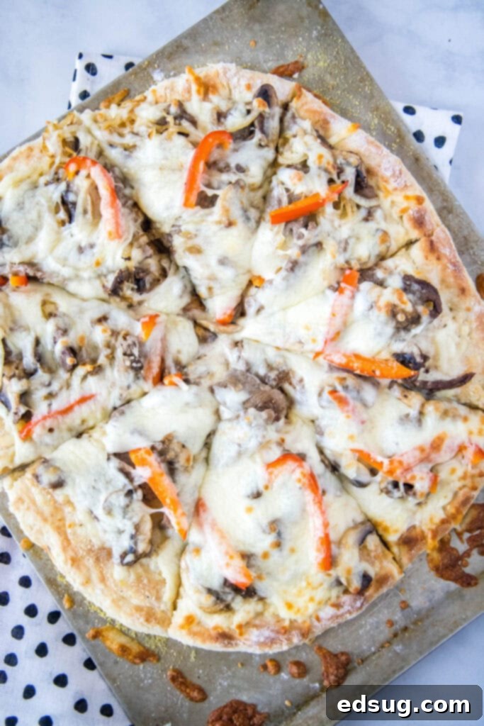Philly Steakhouse Pizza 5 Top-down view of a freshly baked Philly Cheesesteak Pizza, sliced and ready to serve on a baking tray.