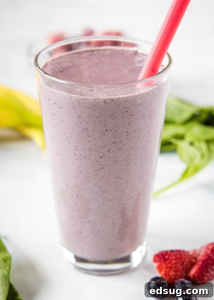 Berry Burst Smoothie 5 Freshly blended mixed berry smoothie in a glass with a straw, placed on a wooden surface