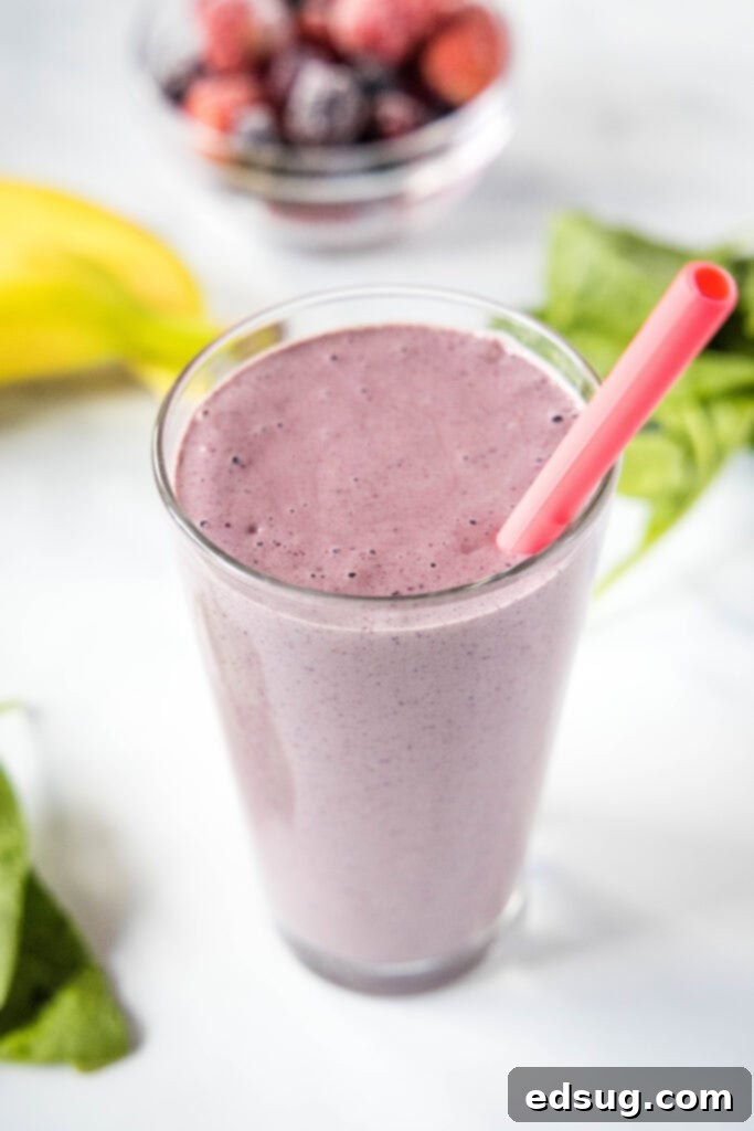 Berry Burst Smoothie 6 Mixed berry smoothie in a glass with a pink striped straw, on a light-colored background