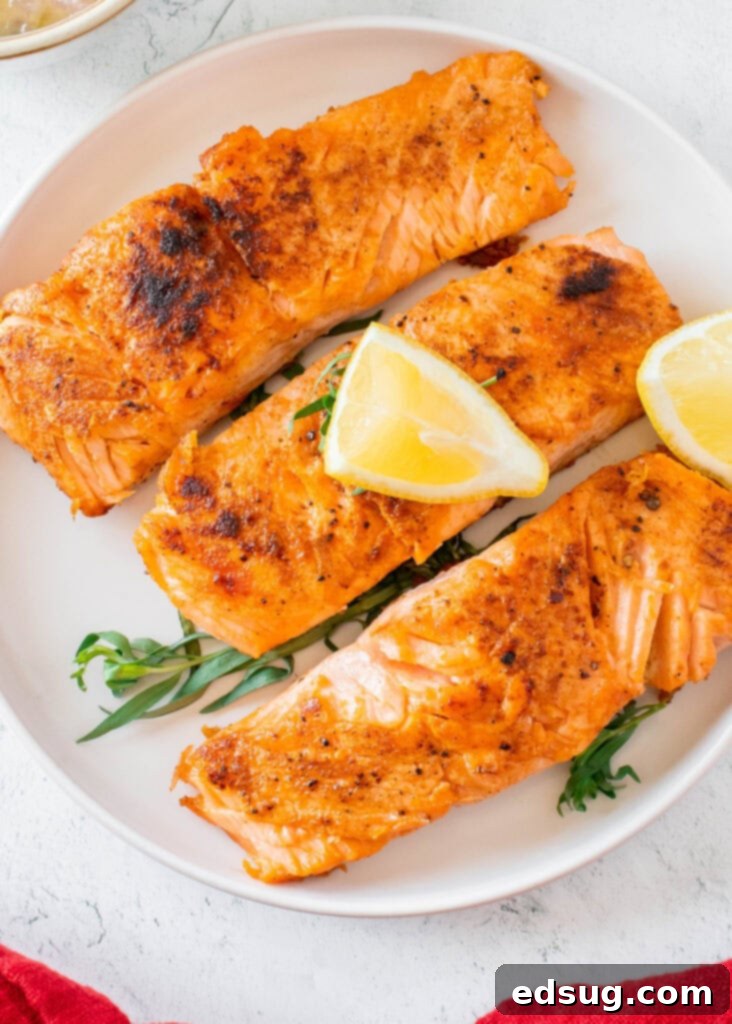 Seared Salmon Perfection 2 Perfectly pan-seared salmon fillet on a plate with lemon slices and fresh herbs