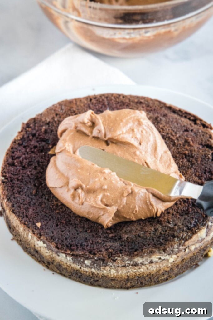 Hands frosting a delicious air fryer chocolate cake with smooth chocolate icing.