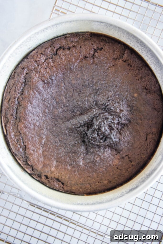A chocolate cake baking in a metal pan inside an air fryer basket.