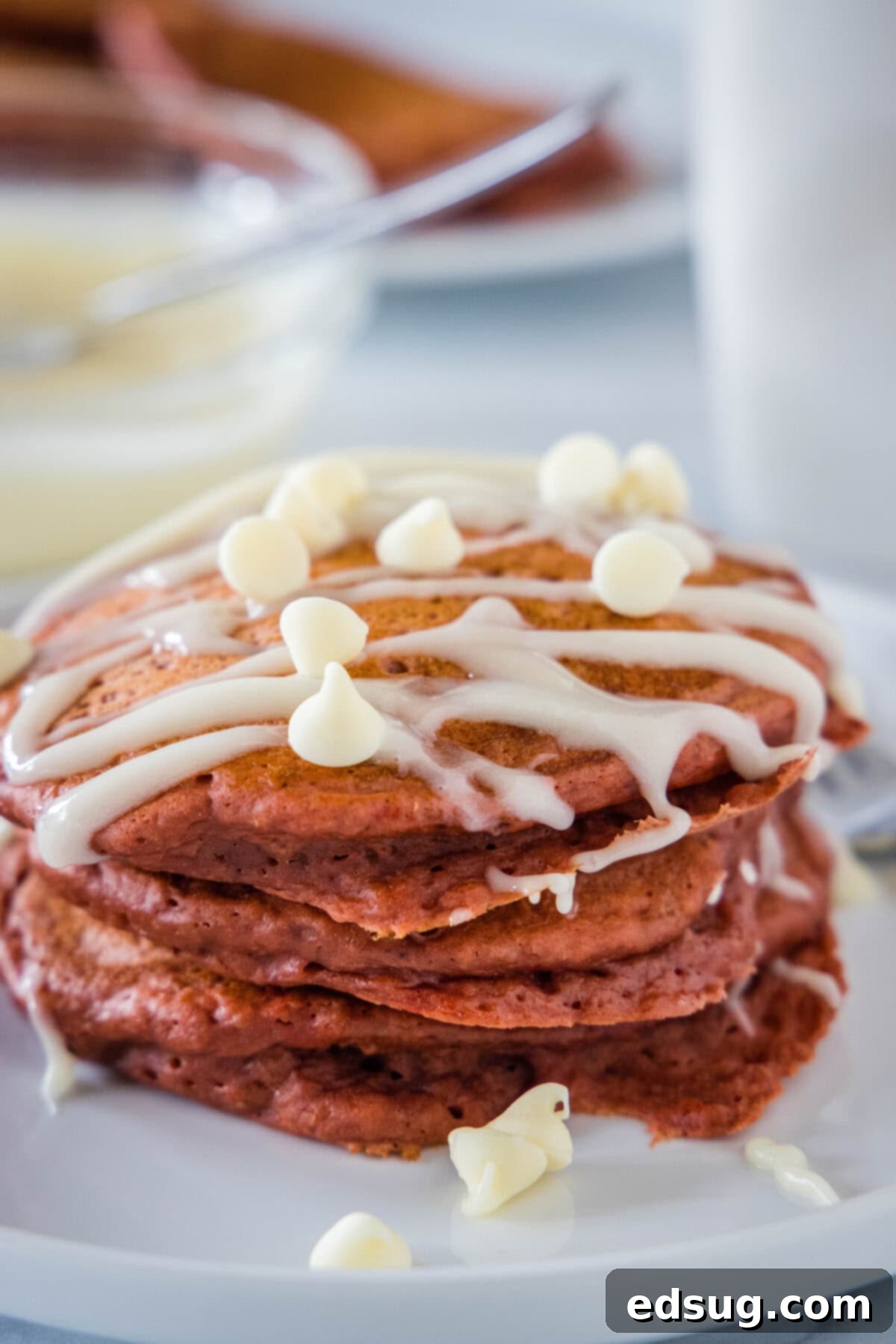 Red Velvet Pancakes | @dinnersdishesdessert red velvet pancakes topped with cream cheese glaze on a white plate