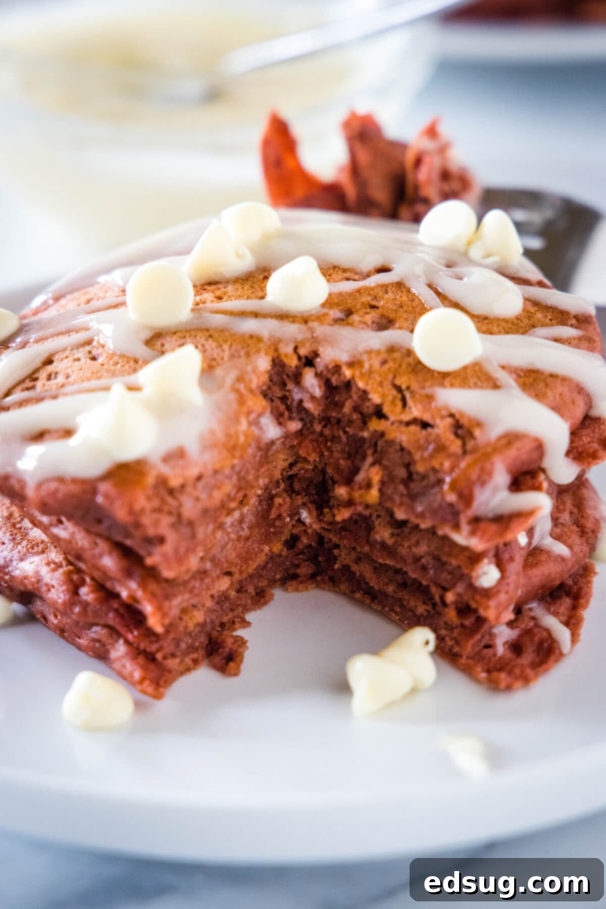 Decadent Red Velvet Pancakes 4 red velvet pancakes stacked with a bite cut from them
