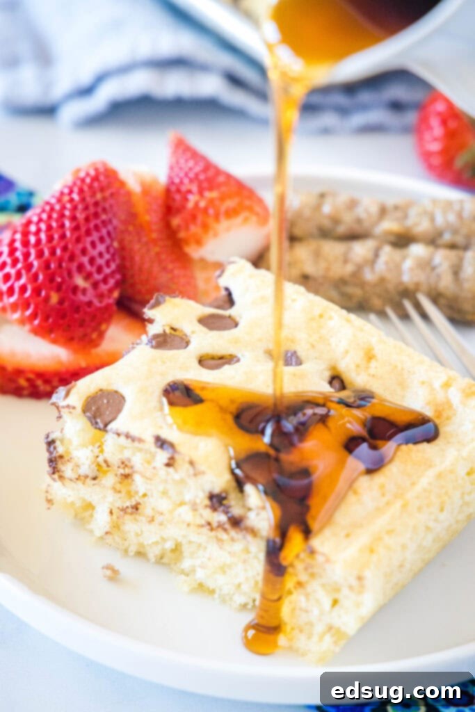 Pouring syrup on a slice of sheet pan pancake on a white plate