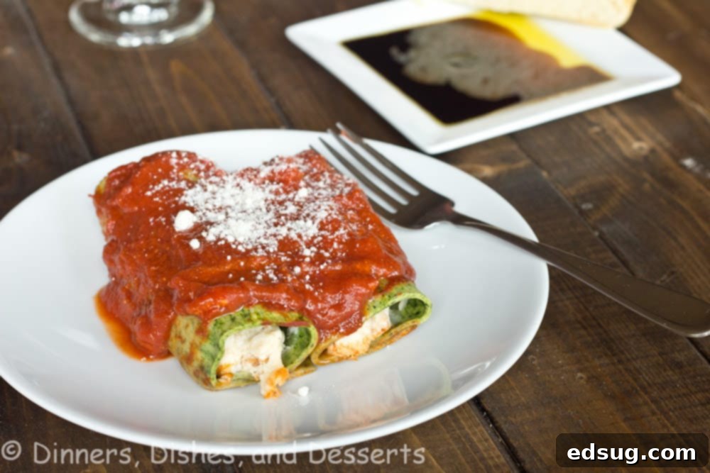 Close-up of freshly made spinach pasta cannelloni, golden brown from baking, nestled in marinara sauce with melted cheese.