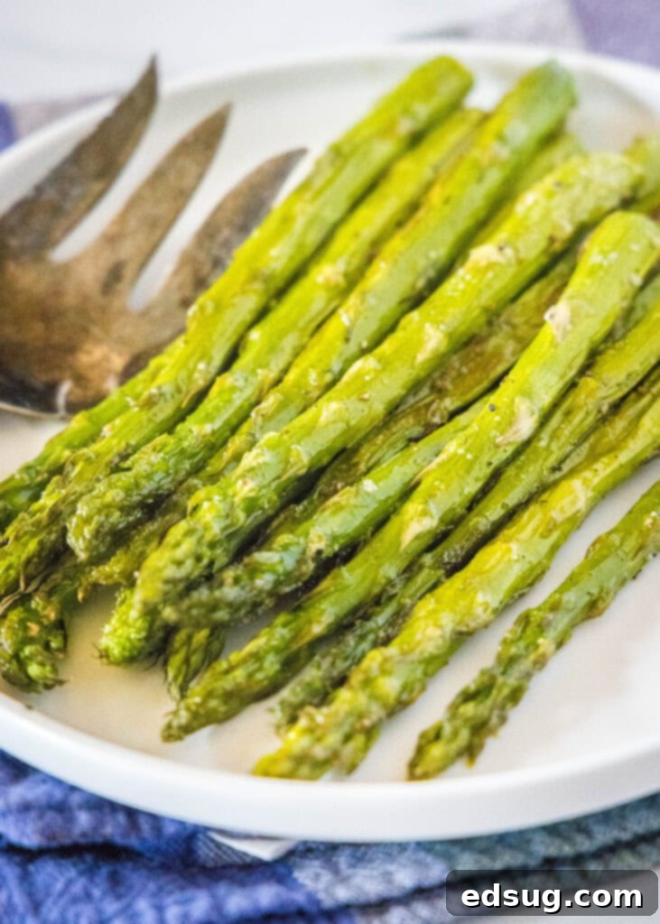 Close-up of perfectly roasted asparagus spears on a white plate, showcasing their golden brown tips and vibrant green stalks.