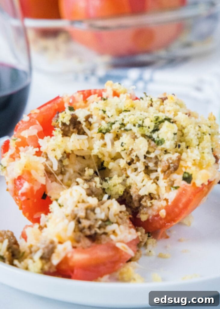 stuffed tomato on a white plate, cut open with rice and sausage