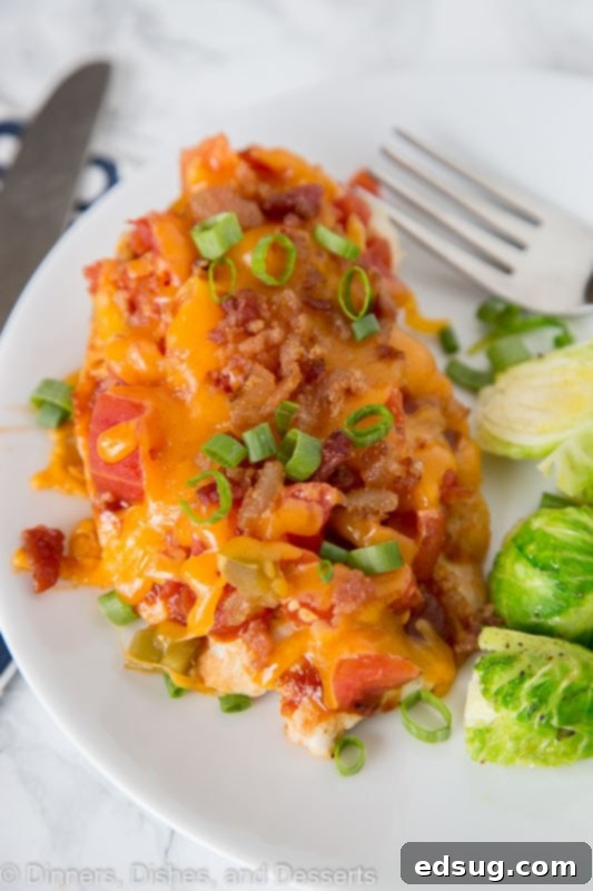 Loaded Monterey Chicken 2 A close up of a plate of food with chicken topped with tomatoes, bacon and melted cheese, ready to be served