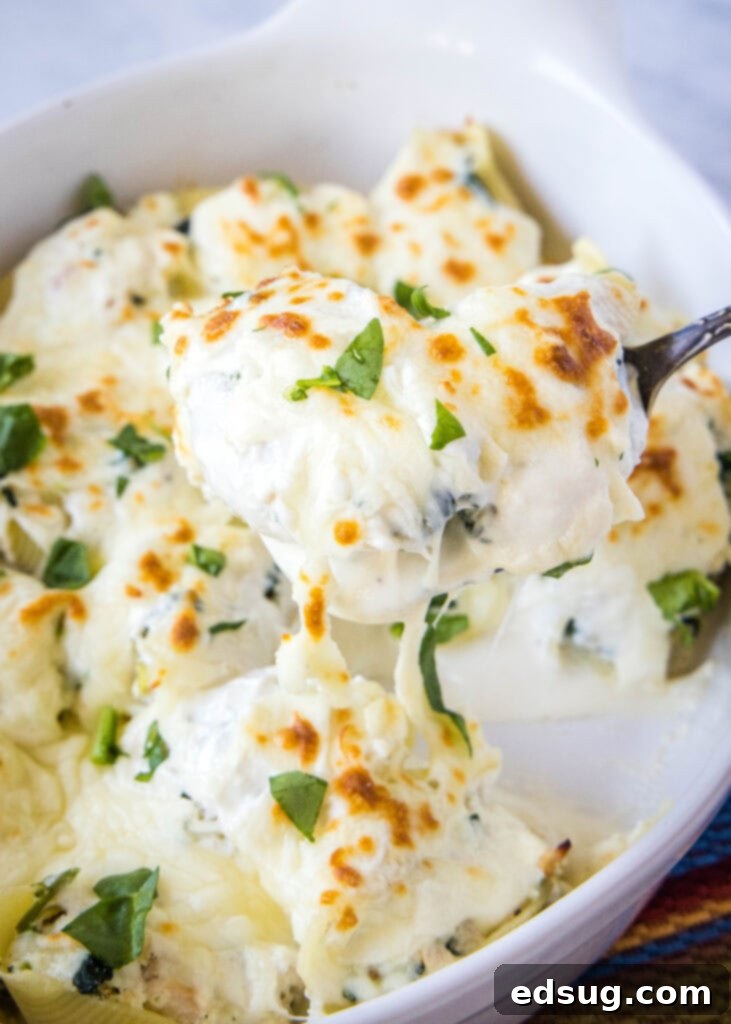 Creamy Chicken Stuffed Shells 7 Scooping a generous portion of chicken stuffed shells out of a baking dish, showcasing the creamy sauce and tender pasta