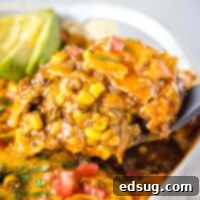 close up scooping beef enchilada casserole out of the pan
