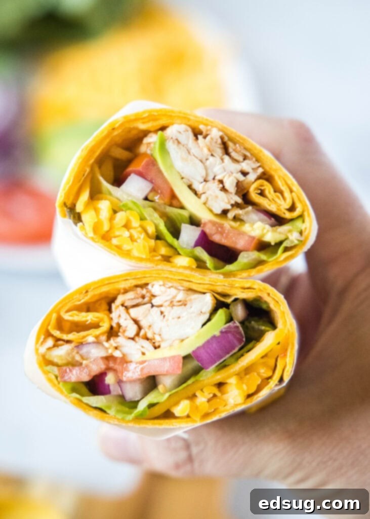 hand holding a bbq chicken wrap cut in half