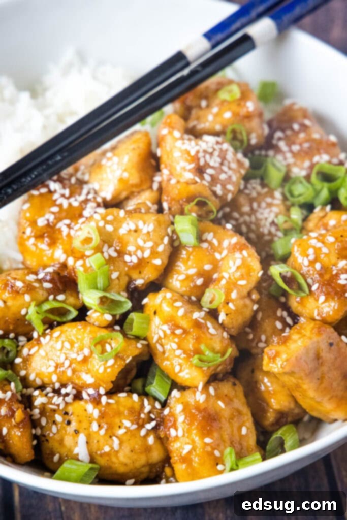 A bowl of delicious Bourbon Chicken with rice and chopsticks, ready to eat