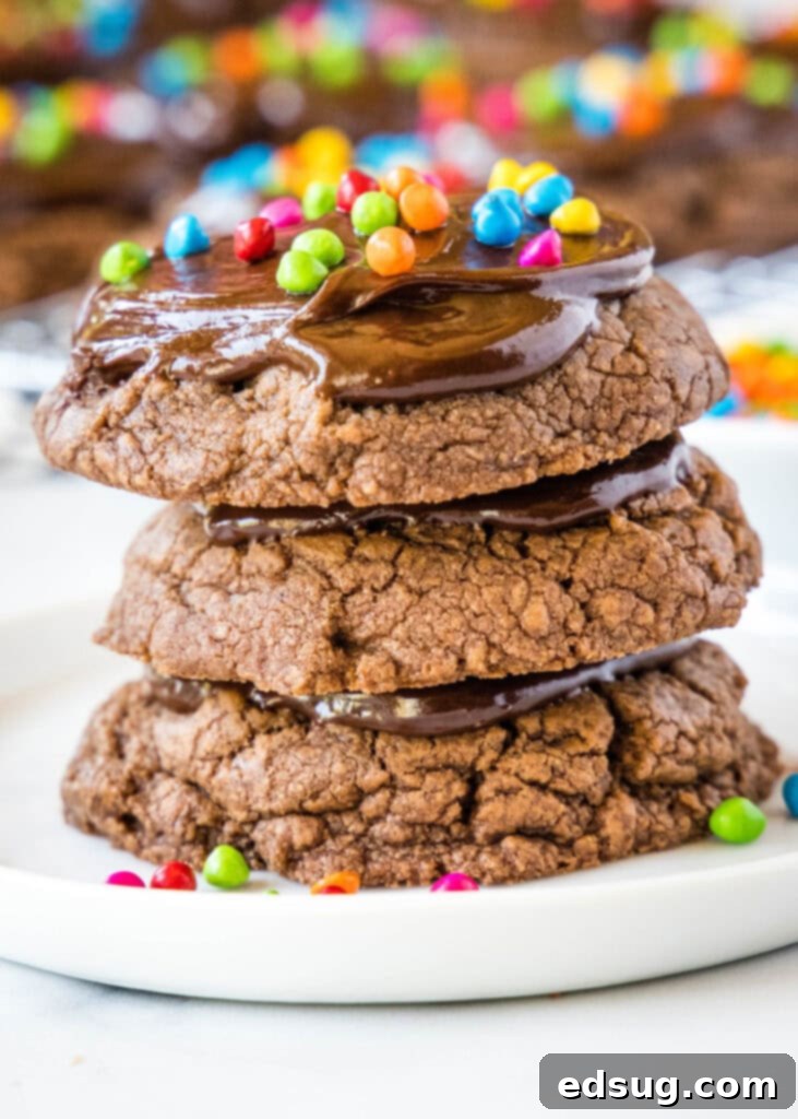 Stellar Brownie Cookies 6 A stack of perfectly baked Cosmic Brownie Cookies on a white plate, topped with smooth chocolate ganache and colorful sprinkles, ready to be enjoyed.