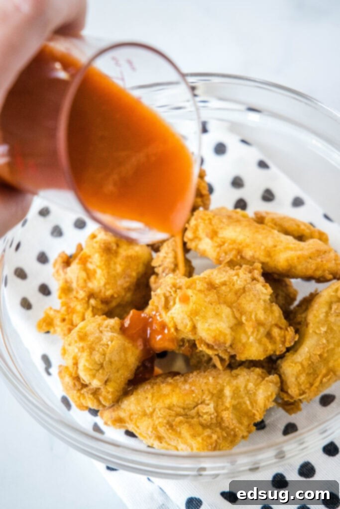 Crispy Chicken Poppers 4 pouring sauce over breaded chicken pieces in a bowl