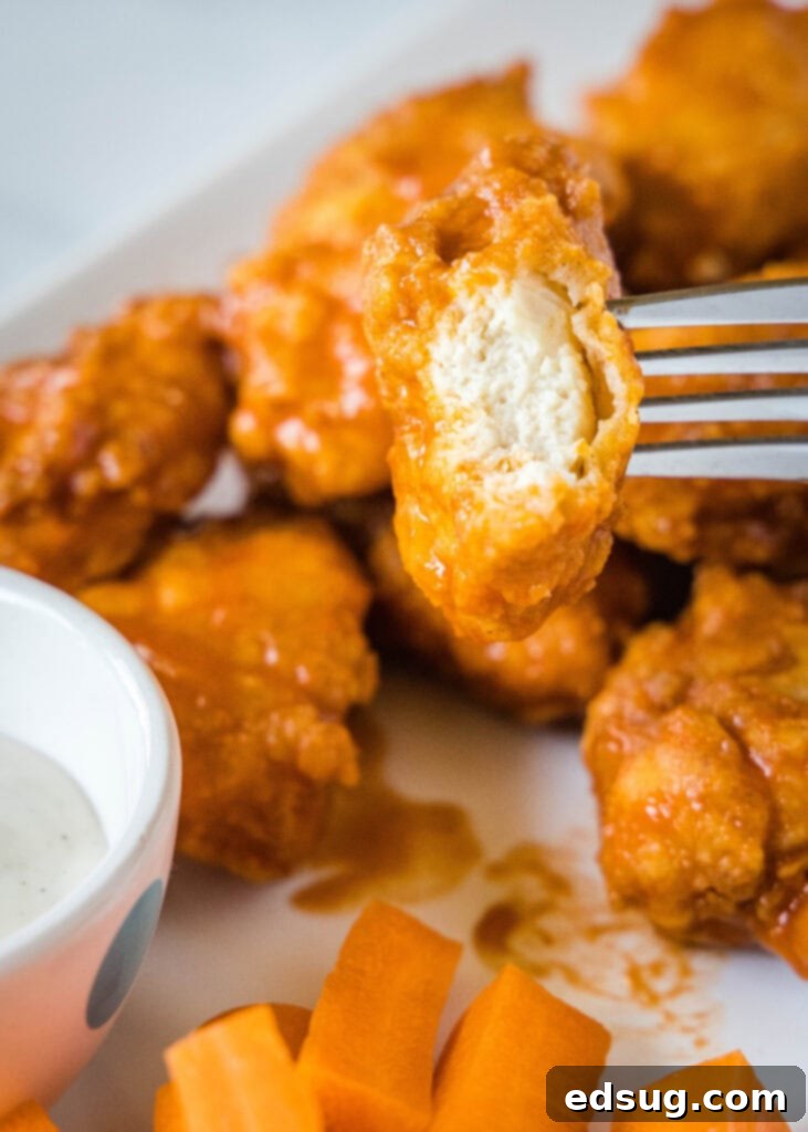 Crispy Chicken Poppers 6 a piece of chicken on a fork with a bite out of it