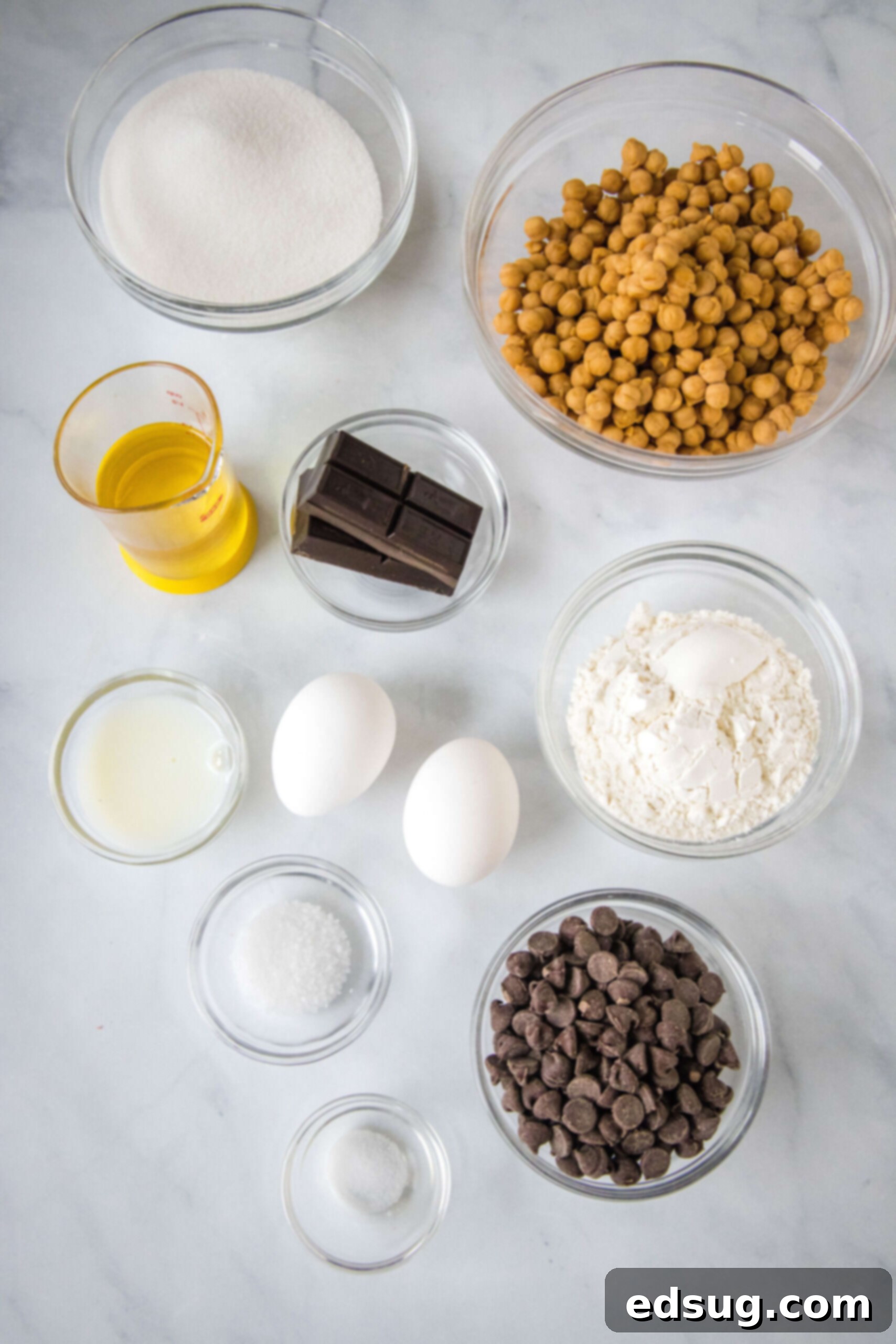 Gather your ingredients: chocolate, oil, eggs, sugar, flour, chocolate chips, caramels, milk, and sea salt for the best salted caramel brownies. Essential ingredients for making fudgy salted caramel brownies laid out on a clean surface.