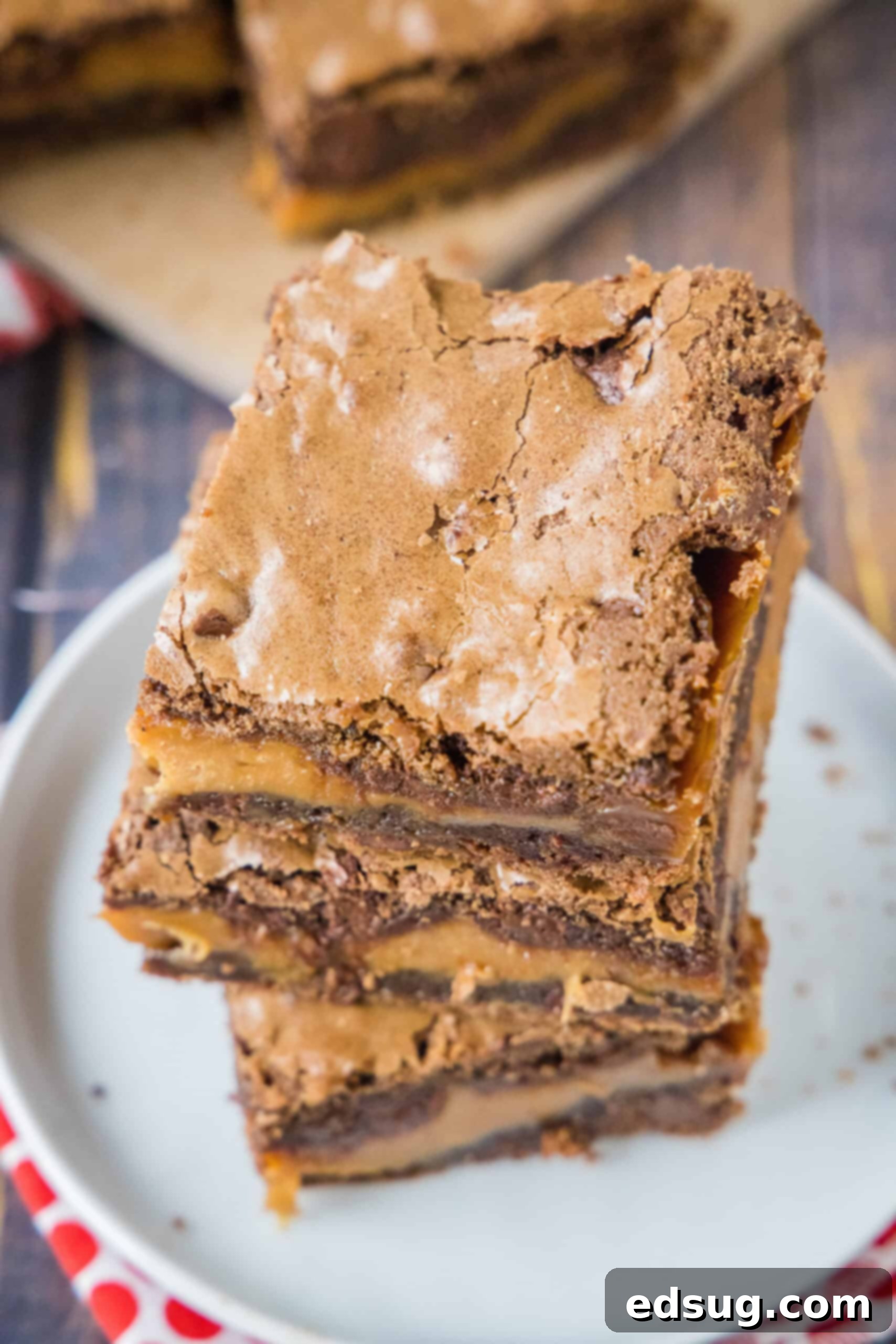 Feast your eyes on these beautifully stacked salted caramel brownies – a true dessert masterpiece. An overhead shot showcasing three perfectly sliced salted caramel brownies, neatly stacked on a pristine white plate.