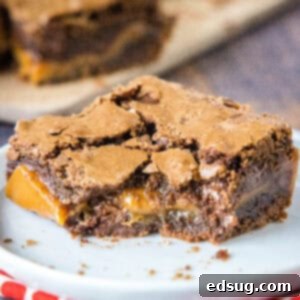 Decadent Salted Caramel Brownies 2 Close up of a salted caramel brownie with a bite missing on a white plate, revealing the gooey caramel.