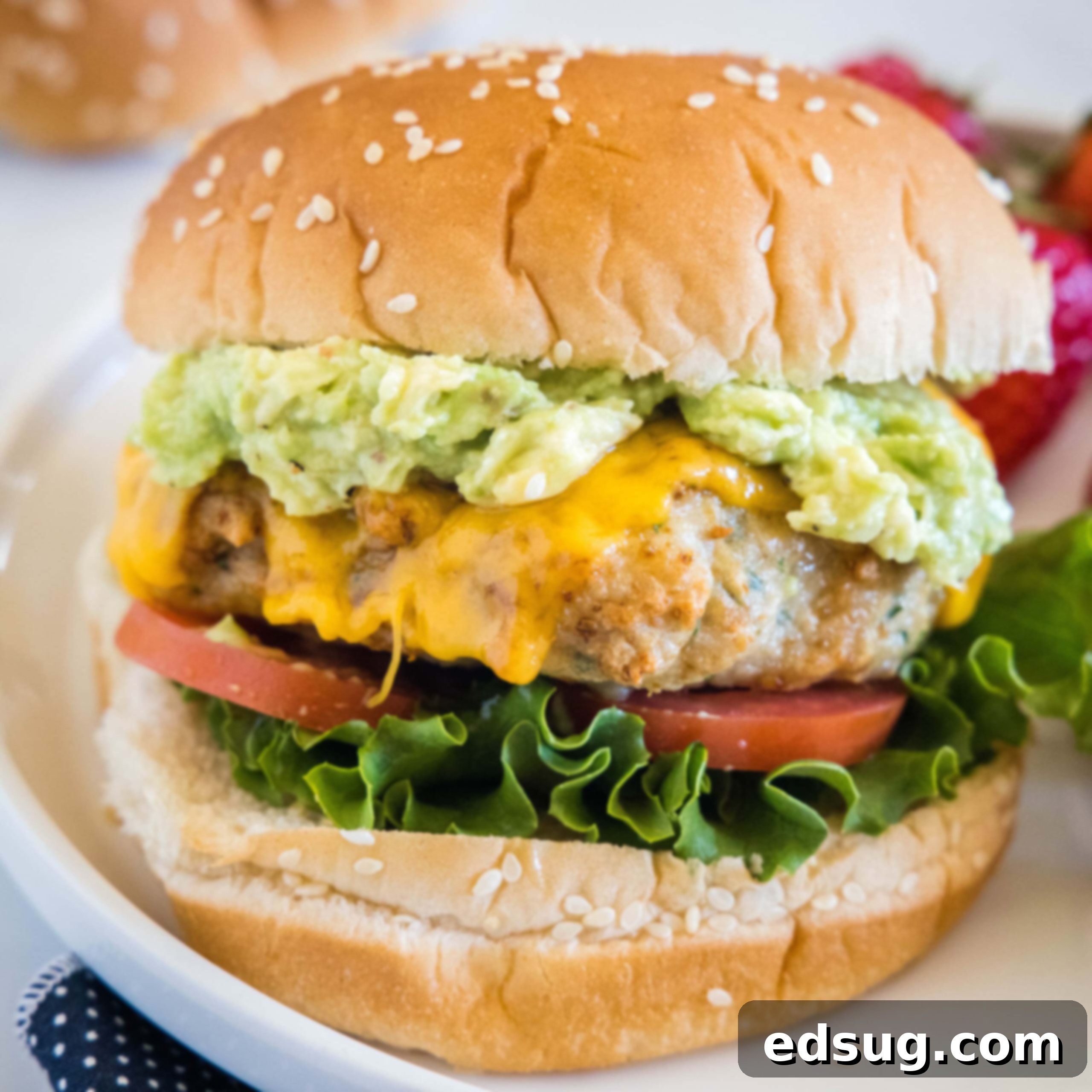 An air fryer chicken burger stacked with all the fixings on a white plate.