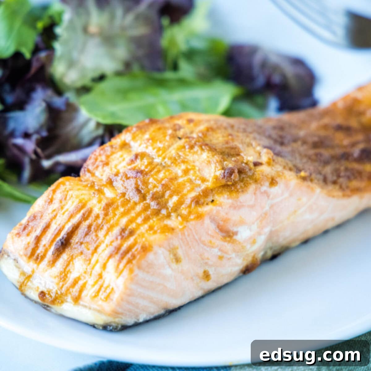 Close up of a salmon fillet on a plate with a salad.