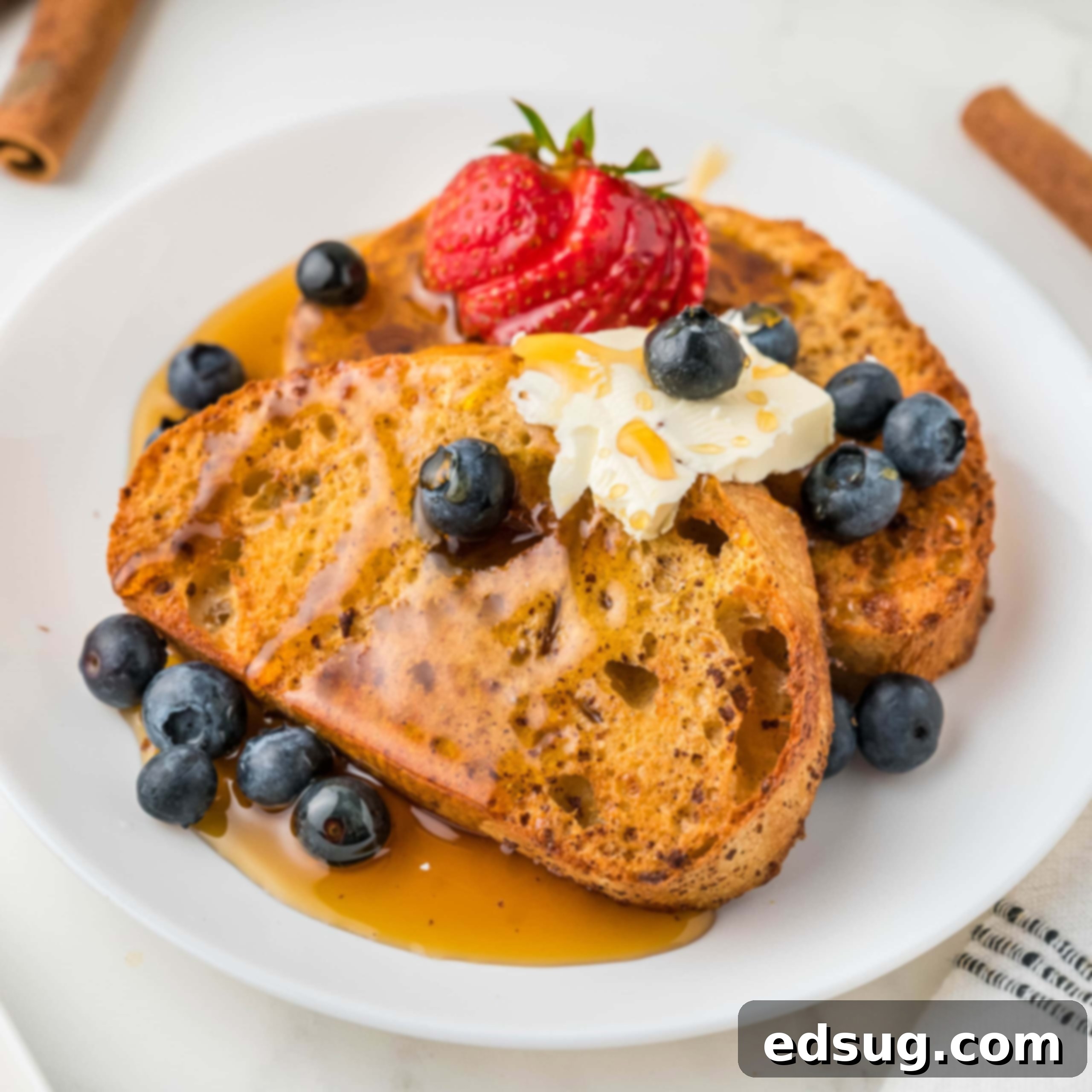 cropped close up air fryer french toast on a white plate with syrup and berries