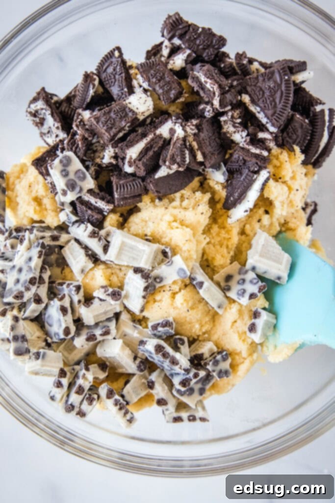 cookie dough in a bowl with crushed oreo cookies and white chocolate bars