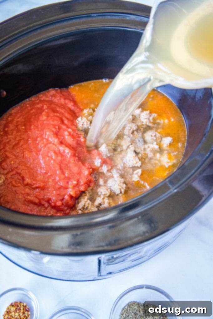 pouring chicken broth into crockpot