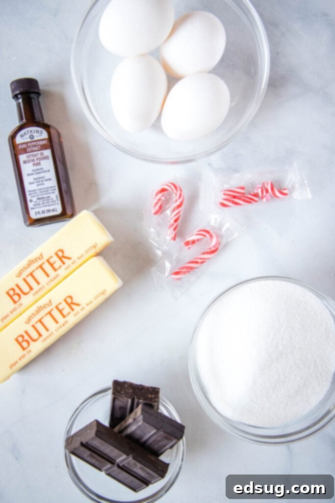 Decadent Peppermint French Silk Pie 3 A collection of essential ingredients for Peppermint French Silk Pie neatly arranged on a kitchen counter, including sticks of butter, a bowl of granulated sugar, unsweetened chocolate squares, fresh eggs, and a bottle of peppermint extract.