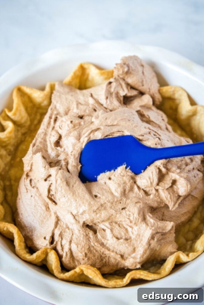 Decadent Peppermint French Silk Pie 4 Rich, glossy chocolate pie filling expertly poured into a golden-brown, flaky baked pie crust, ready for its chilling phase.