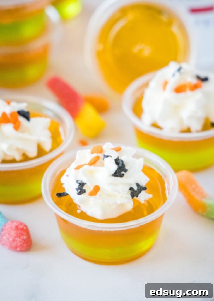 Witches Brew Jello Shots 5 Finished Halloween Jello Shots, layered in orange and green, generously topped with whipped cream and a sprinkle of festive Halloween decorations.