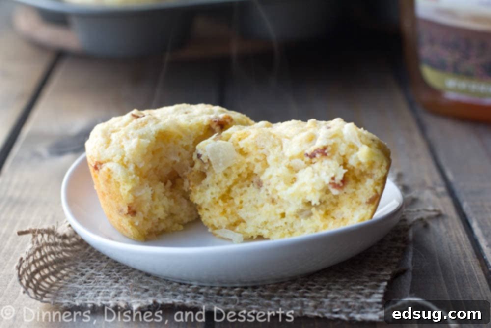 A close-up shot of several freshly baked bacon, cheddar, and onion corn muffins on a rustic plate, highlighting their golden crust and savory inclusions.
