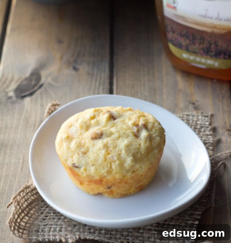 An overhead view of a plate filled with golden-brown bacon, cheddar, and onion corn muffins, ready to be served.