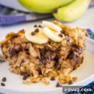A close-up of a single serving of banana baked french toast on a white plate, drizzled with maple syrup.