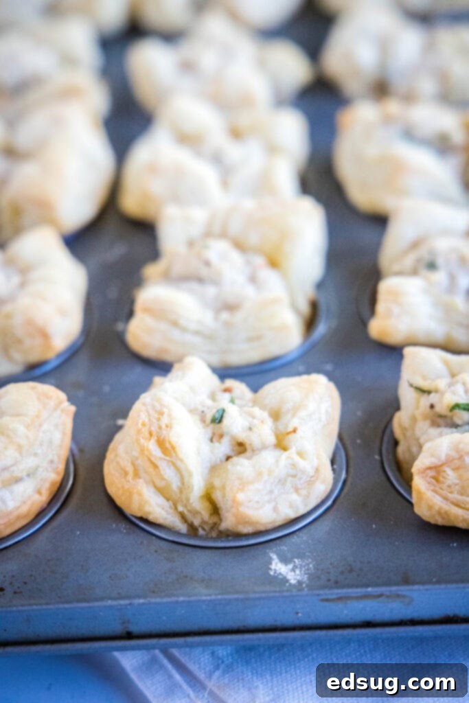 baked golden brown crab puffs cooling in a mini muffin tin after being removed from the oven