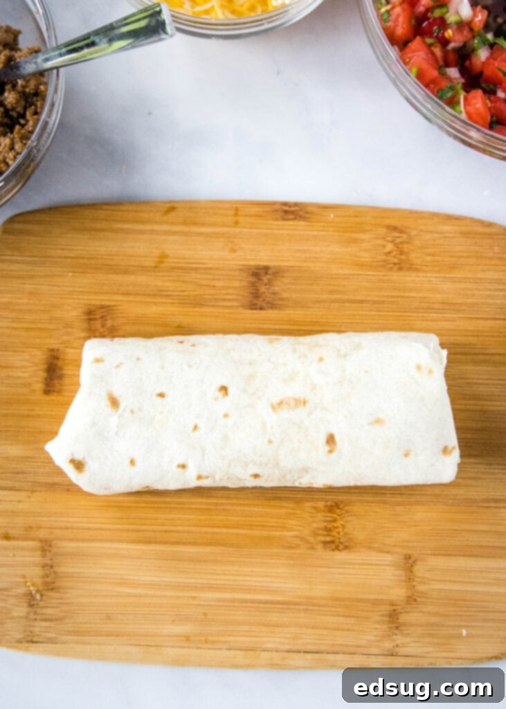 Taco Bell Copycat Meximelt Recipe 5 rolled up tortilla like a burrito on a cutting board