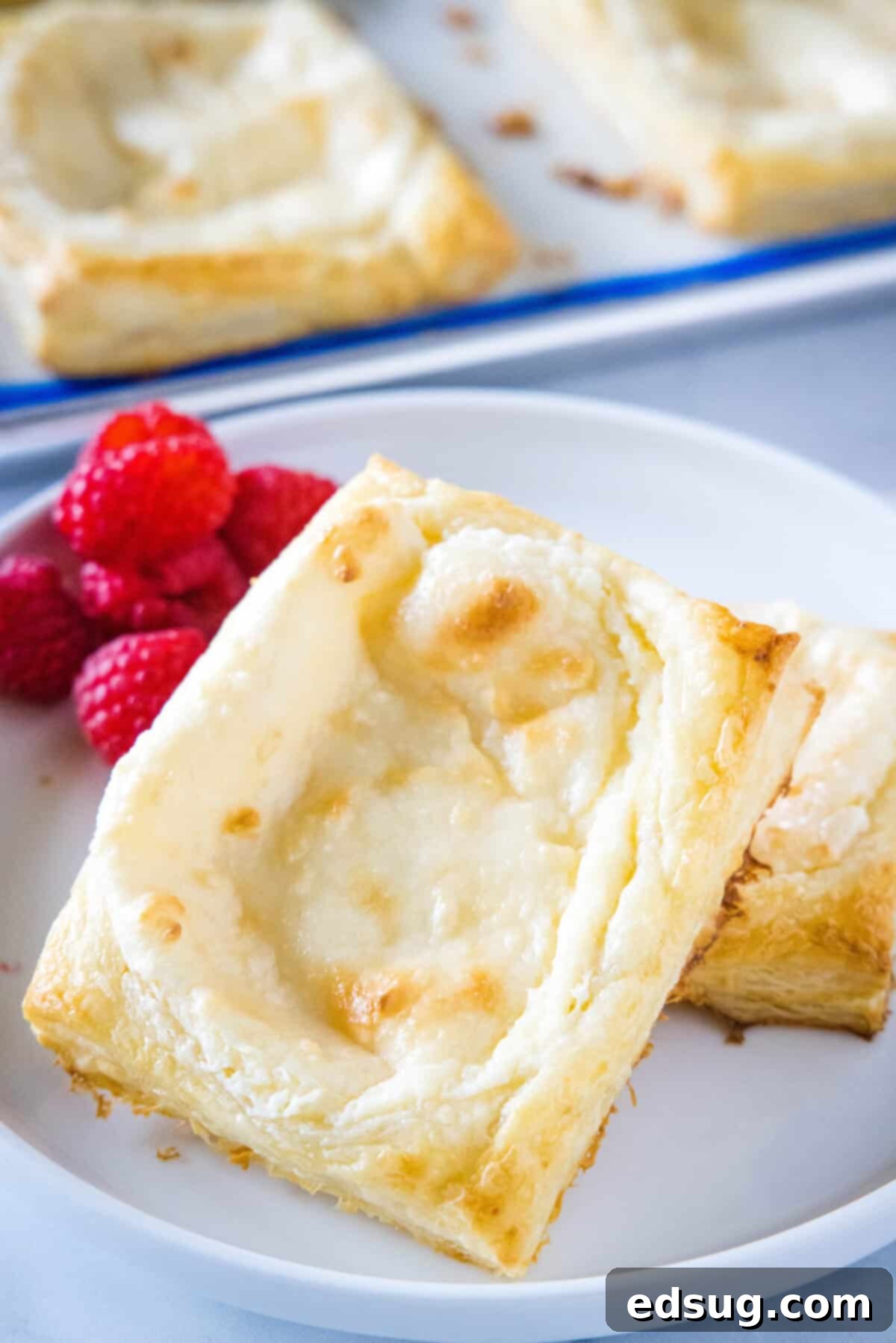 Quick Cream Cheese Danishes A single cream cheese danish on a white plate, showing the puffed edges and creamy center