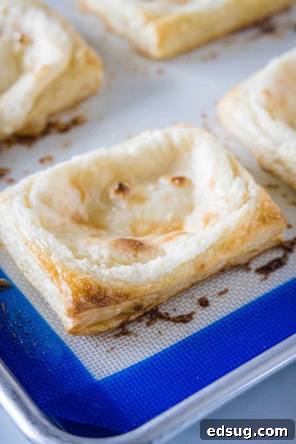 Decadent Cream Cheese Danish 6 Multiple cream cheese danishes arranged on a parchment-lined baking tray, ready for the oven