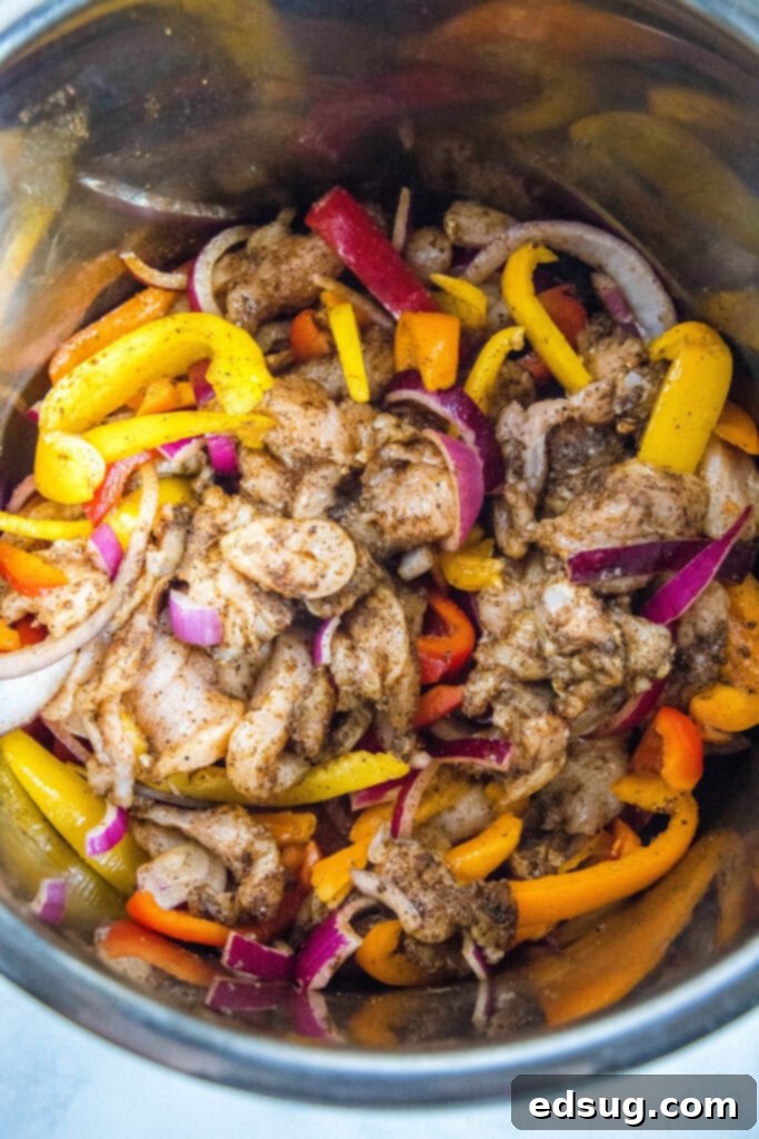 Seasoned chicken and bell pepper mixture inside the Instant Pot before cooking.