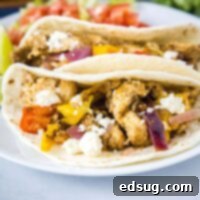 Close up square image of chicken fajitas on a white plate.